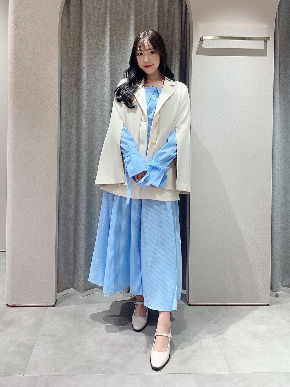 ブルー系のシャツワンピース、ホワイト系のテーラードジャケット、ホワイト系のパンプスを着用したレディースの冬コーディネートの6枚目の写真