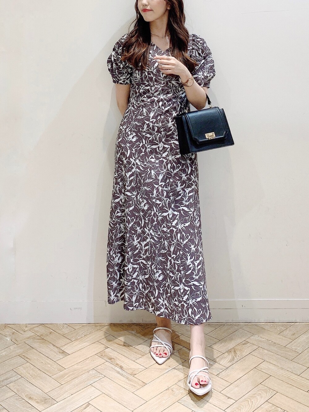 グレー系のワンピース、ホワイト系のサンダル、ブラック系のハンドバッグを着用したレディースの春コーディネートの2枚目の写真