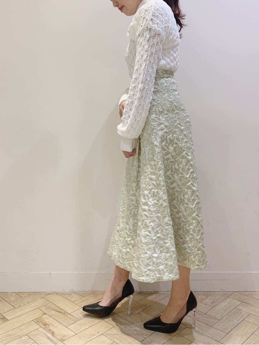 グリーン系のスカート、ホワイト系のニット/セーターを着用したレディースの春コーディネートの2枚目の写真