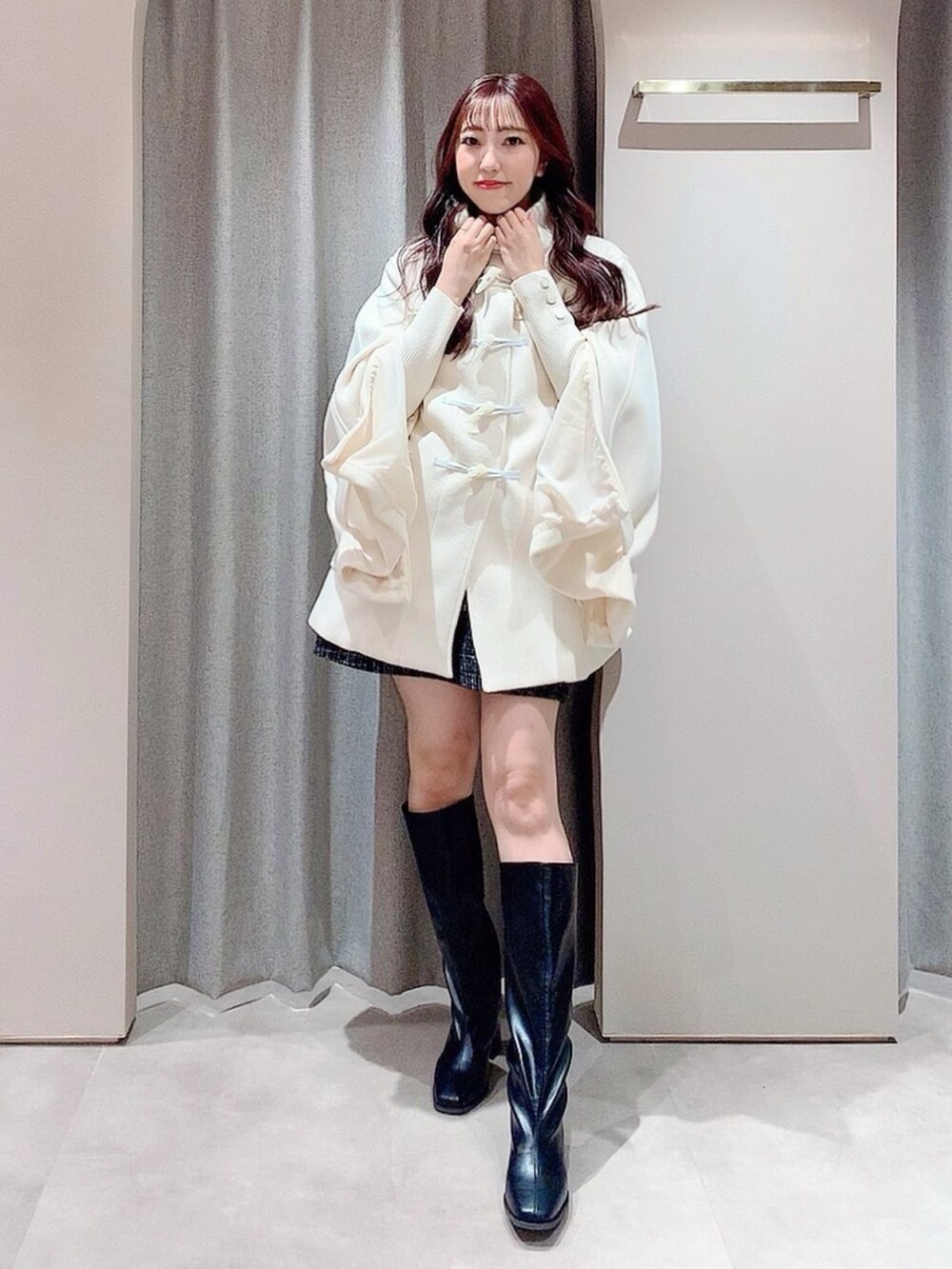 ホワイト系のダッフルコート、ホワイト系のニット/セーター、ブラック系のスカートを着用したレディースの秋コーディネートの2枚目の写真