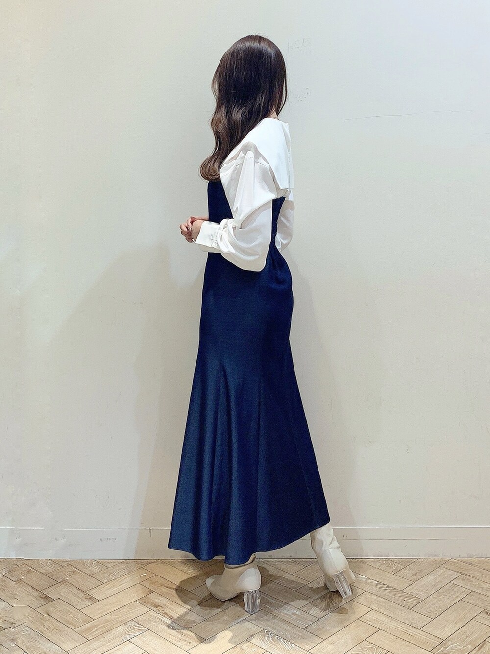 ブルー系のワンピース、ホワイト系のブーツ、ベージュ系のステンカラーコートを着用したレディースの冬コーディネートの3枚目の写真