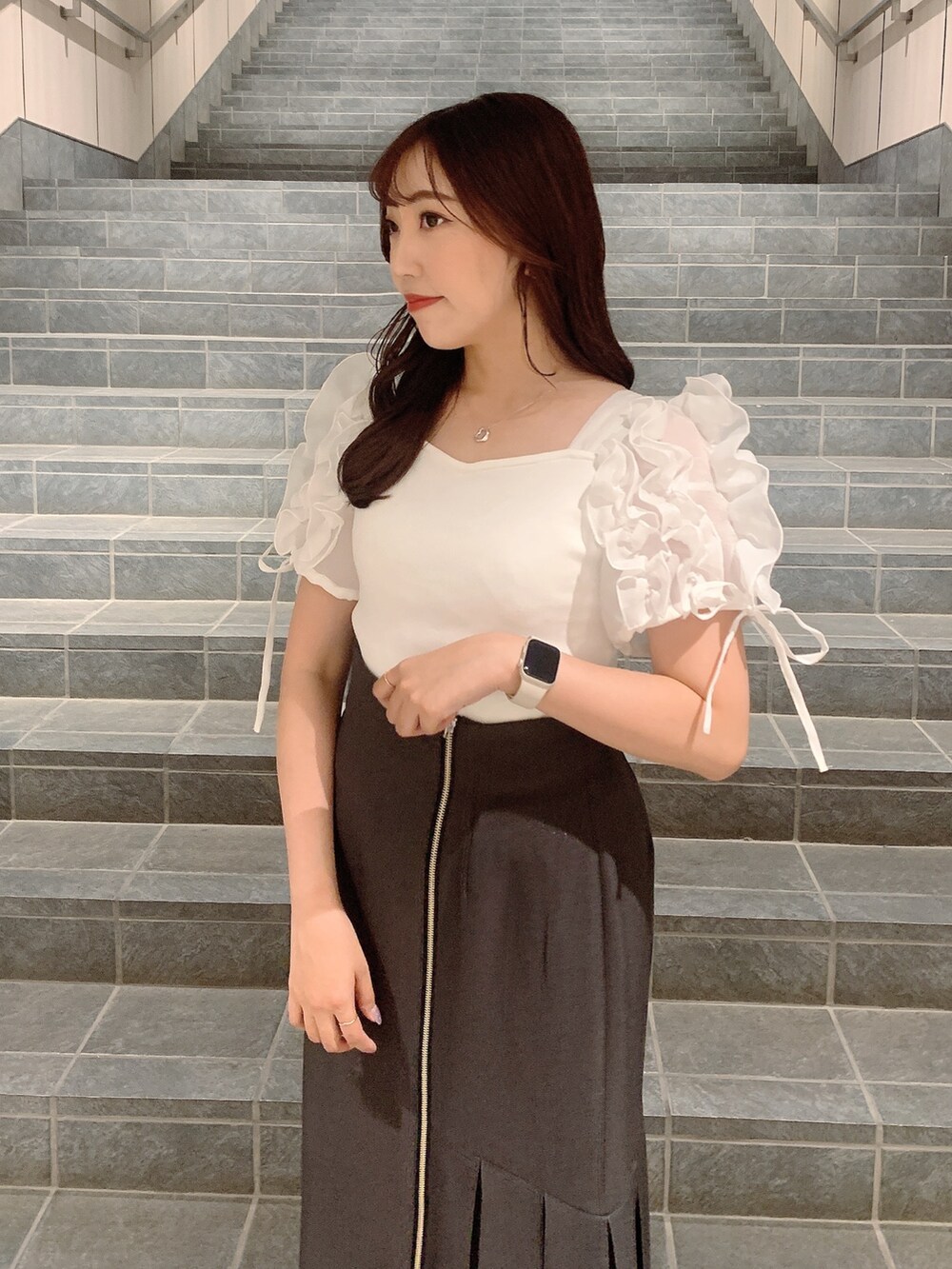 ブラウン系のスカート、シルバー系のパンプス、ホワイト系のTシャツ/カットソーを着用したレディースの夏コーディネートの7枚目の写真