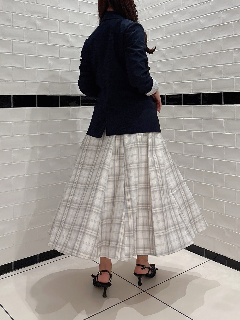 イエロー系のスカート、パープル系のニット/セーター、ブラック系のパンプスを着用したレディースの春コーディネートの6枚目の写真