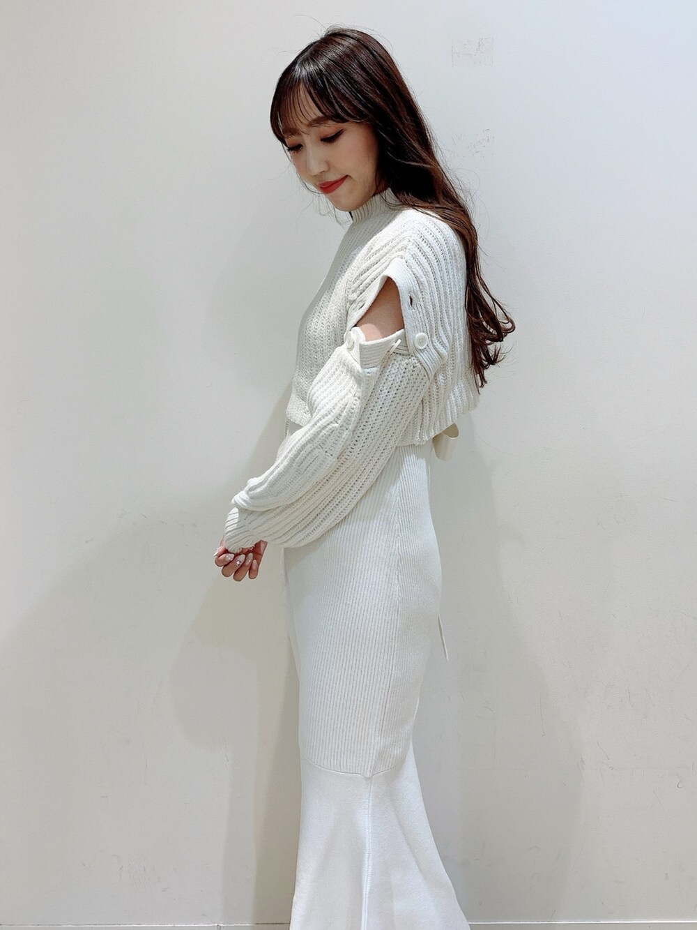 ホワイト系のワンピース、ベージュ系のステンカラーコート、ブラウン系のブーツを着用したレディースの冬コーディネートの6枚目の写真