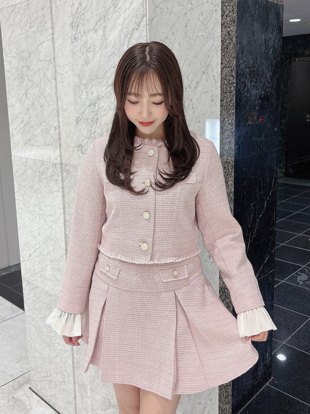 ピンク系のノーカラージャケット、ピンク系のスカート、ホワイト系のブーツを着用したレディースの冬コーディネートの6枚目の写真