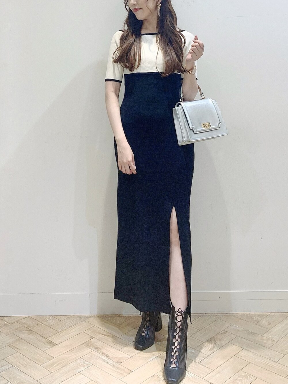 ブラック系のワンピース、シルバー系のハンドバッグ、ブラック系のブーツを着用したレディースの夏コーディネートの3枚目の写真