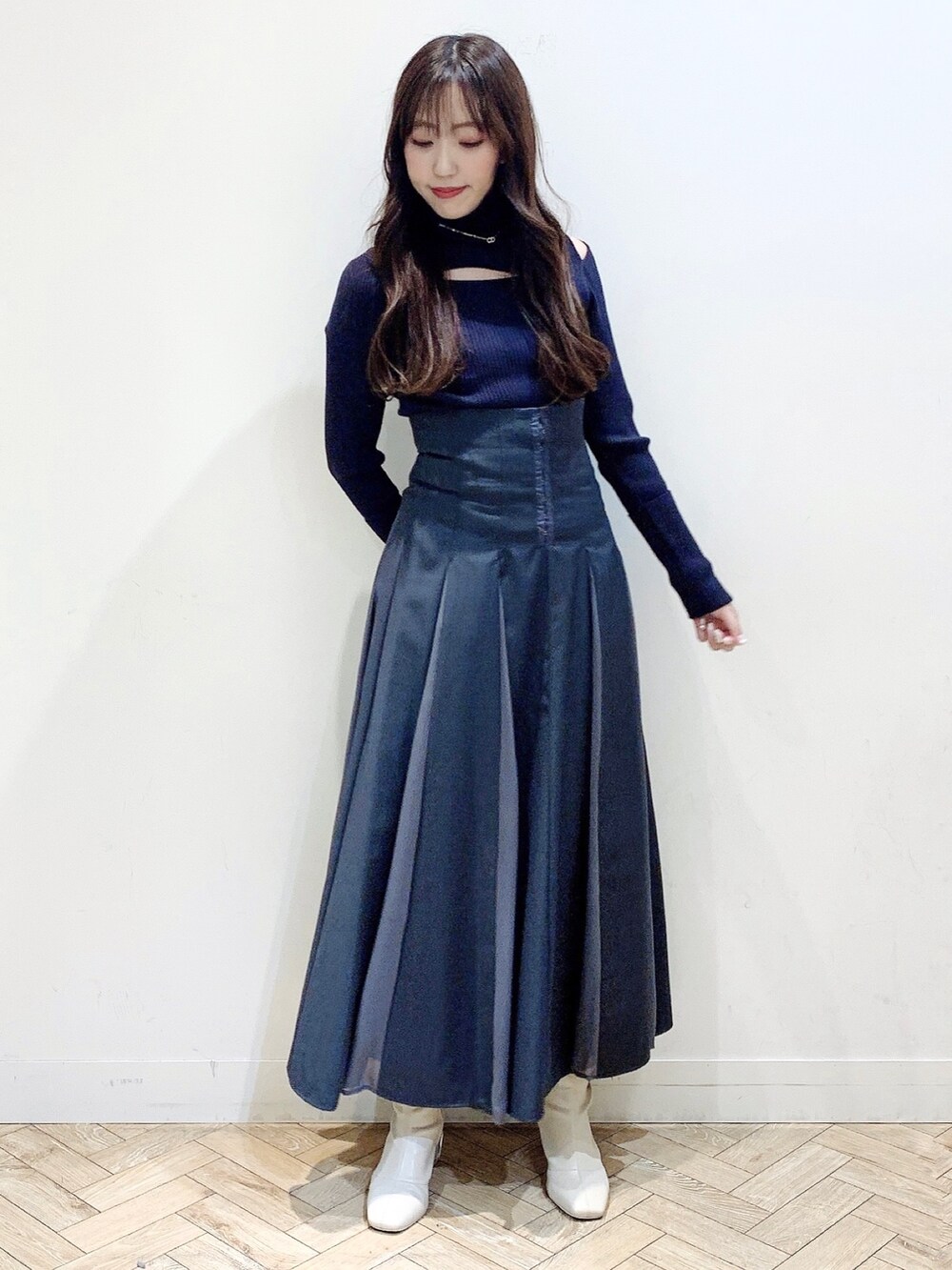 グレー系のニット/セーター、グレー系のスカート、ホワイト系のブーツを着用したレディースの冬コーディネートの2枚目の写真