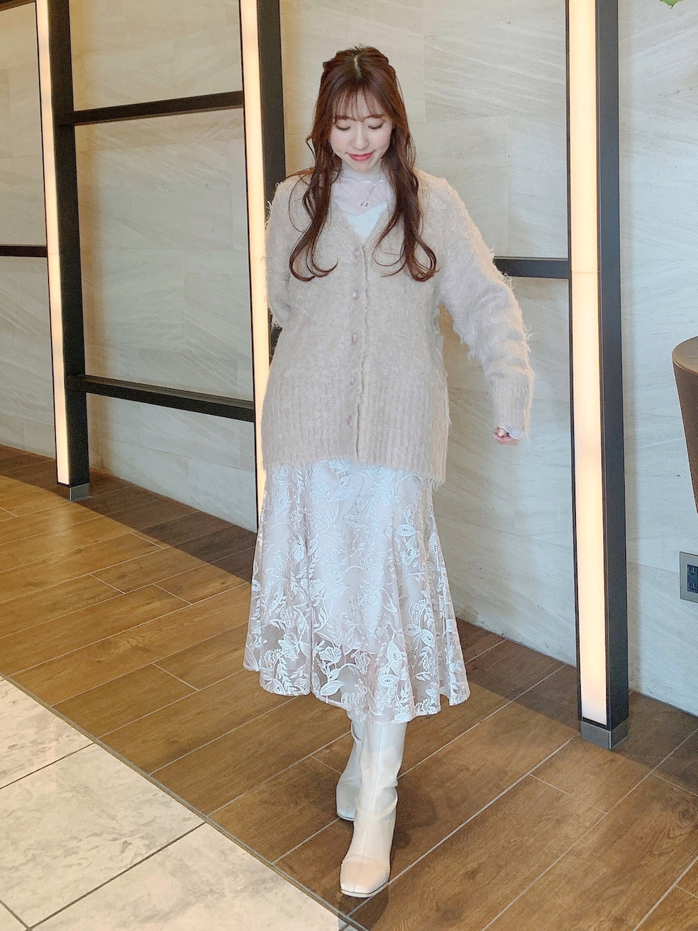 ベージュ系のスカート、ブラウン系のカーディガン/ボレロ、ホワイト系のブーツを着用したレディースの冬コーディネートの2枚目の写真