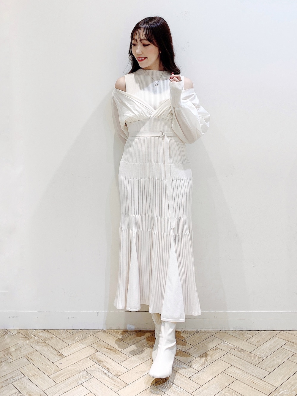 ホワイト系のワンピース、ブラウン系のチェスターコート、ホワイト系のブーツを着用したレディースの冬コーディネートの3枚目の写真