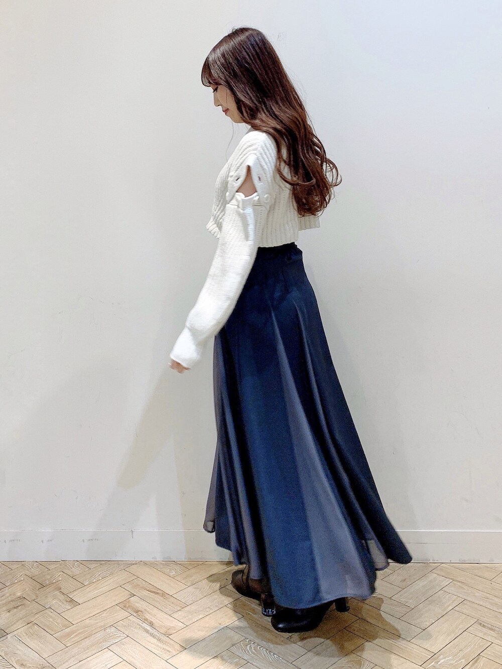 グレー系のスカート、ホワイト系のワンピース、ブラウン系のブーツを着用したレディースの冬コーディネートの4枚目の写真