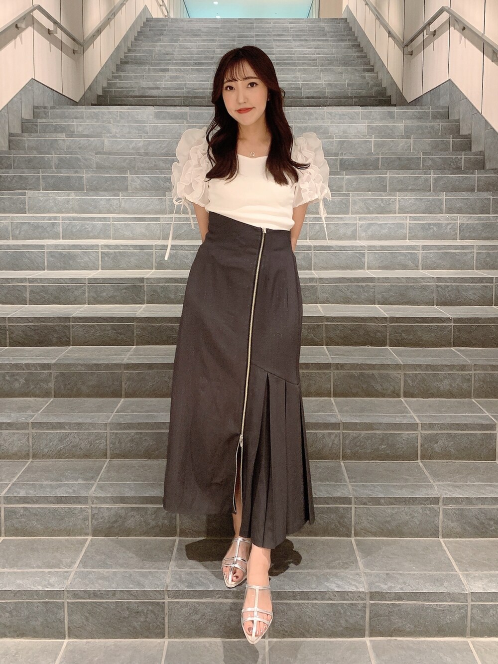 ブラウン系のスカート、シルバー系のパンプス、ホワイト系のTシャツ/カットソーを着用したレディースの夏コーディネートの2枚目の写真