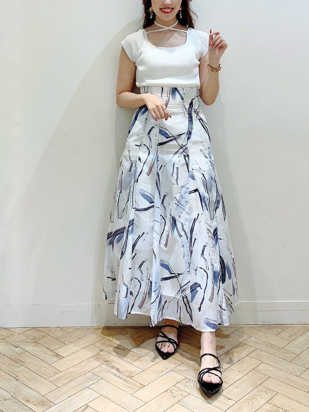 ホワイト系のニット/セーター、グレー系のスカート、ブラック系のサンダルを着用したレディースの夏コーディネートの2枚目の写真