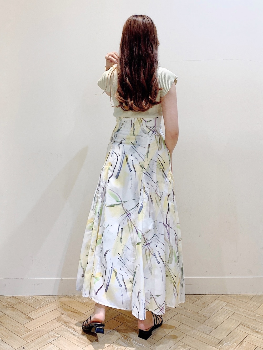 グリーン系のニット/セーター、イエロー系のスカート、ブラック系のサンダルを着用したレディースの夏コーディネートの6枚目の写真