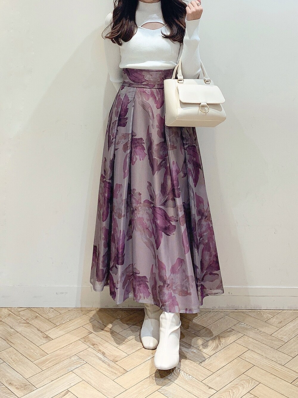 ブラウン系のスカート、ホワイト系のニット/セーター、ホワイト系のハンドバッグを着用したレディースの冬コーディネートの3枚目の写真