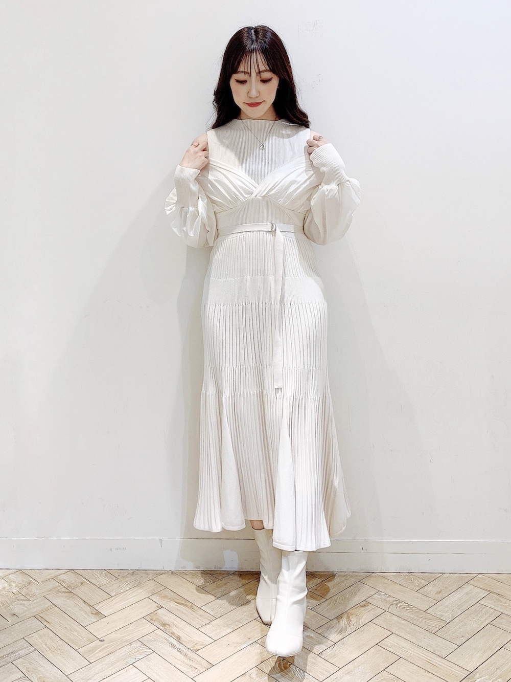 ホワイト系のワンピース、ブラウン系のチェスターコート、ホワイト系のブーツを着用したレディースの冬コーディネートの2枚目の写真