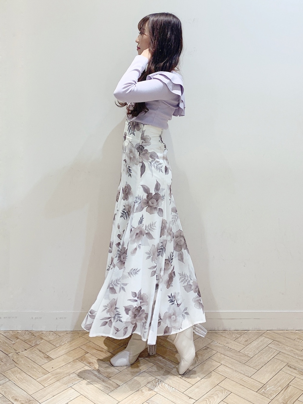 パープル系のニット/セーター、ホワイト系のスカート、ホワイト系のブーツを着用したレディースの冬コーディネートの2枚目の写真