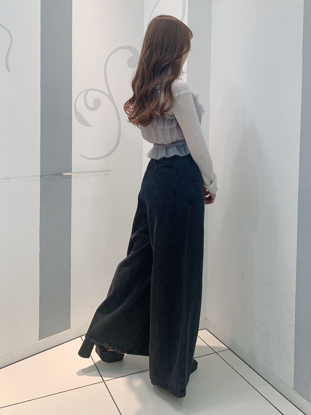 ブラック系のデニムパンツ、ブラック系のパンプス、グレー系のニット/セーターを着用したレディースの秋コーディネートの5枚目の写真