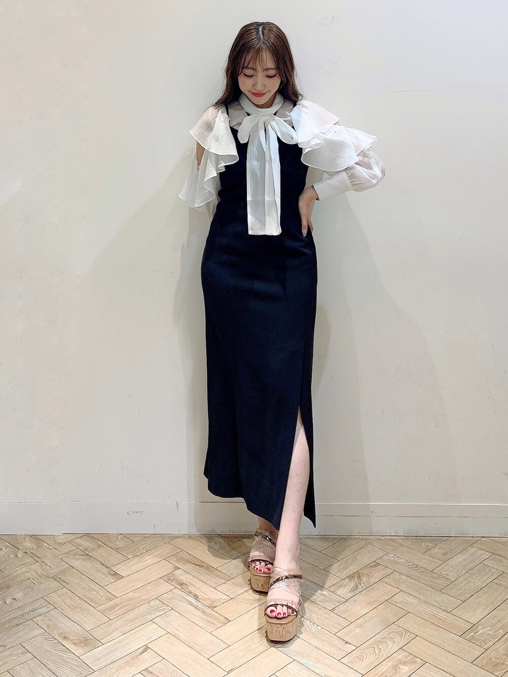 ブラック系のワンピース、ホワイト系のシャツ/ブラウス、ブラウン系のサンダルを着用したレディースの春コーディネートの2枚目の写真