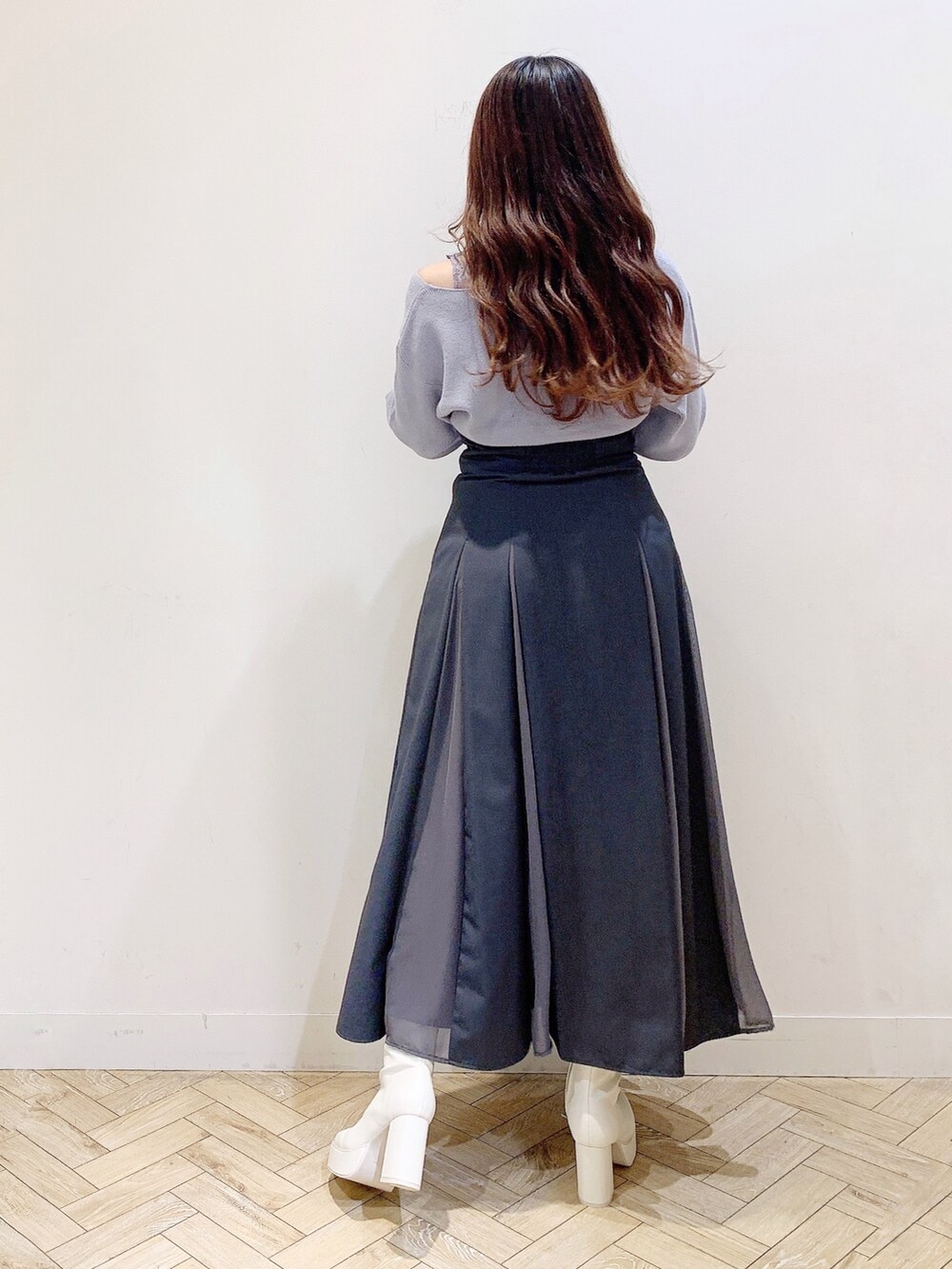 グレー系のスカート、ブルー系のニット/セーター、ホワイト系のブーツを着用したレディースの秋コーディネートの6枚目の写真