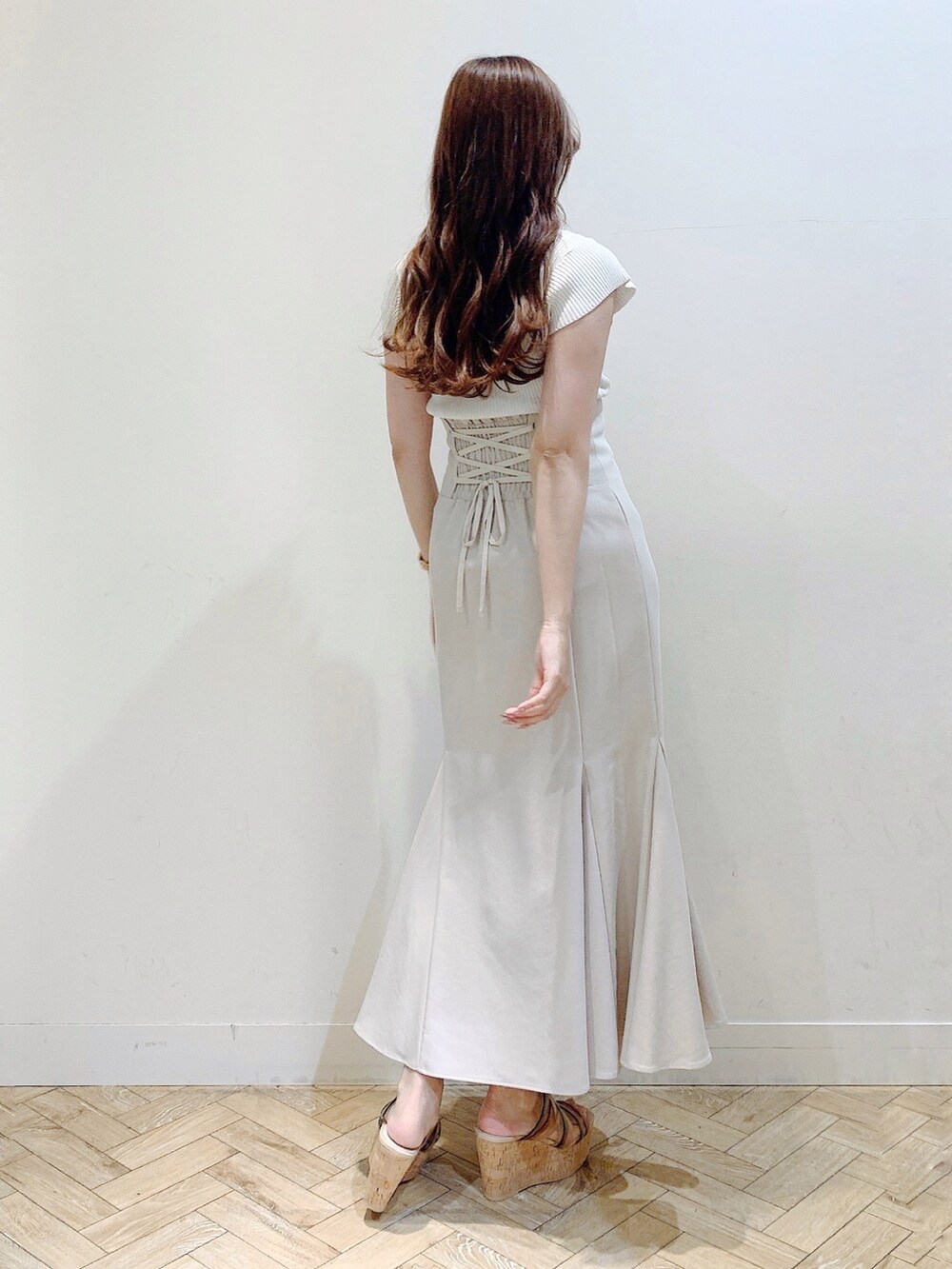 ベージュ系のスカート、ホワイト系のニット/セーター、その他のサンダルを着用したレディースの夏コーディネートの6枚目の写真