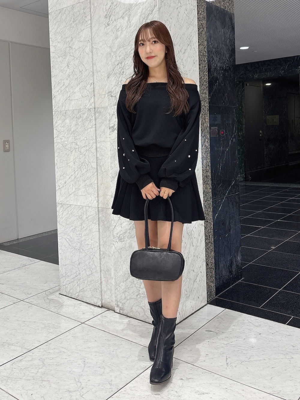 ブラック系のスカート、ブラック系のスウェット、ブラック系のブーツを着用したレディースの秋コーディネートの3枚目の写真