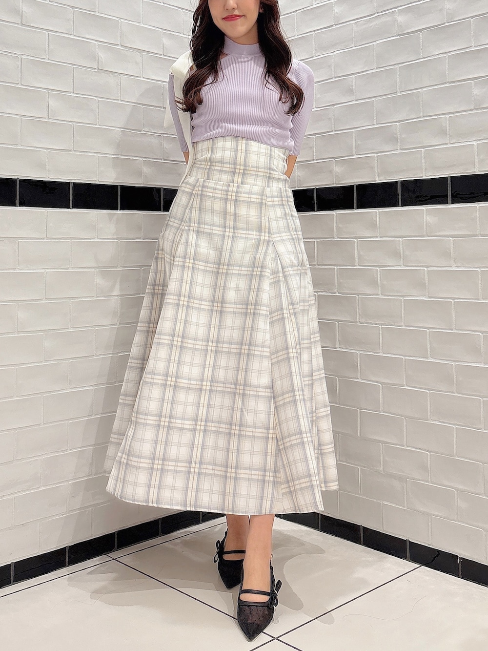 イエロー系のスカート、パープル系のニット/セーター、ブラック系のパンプスを着用したレディースの春コーディネートの2枚目の写真