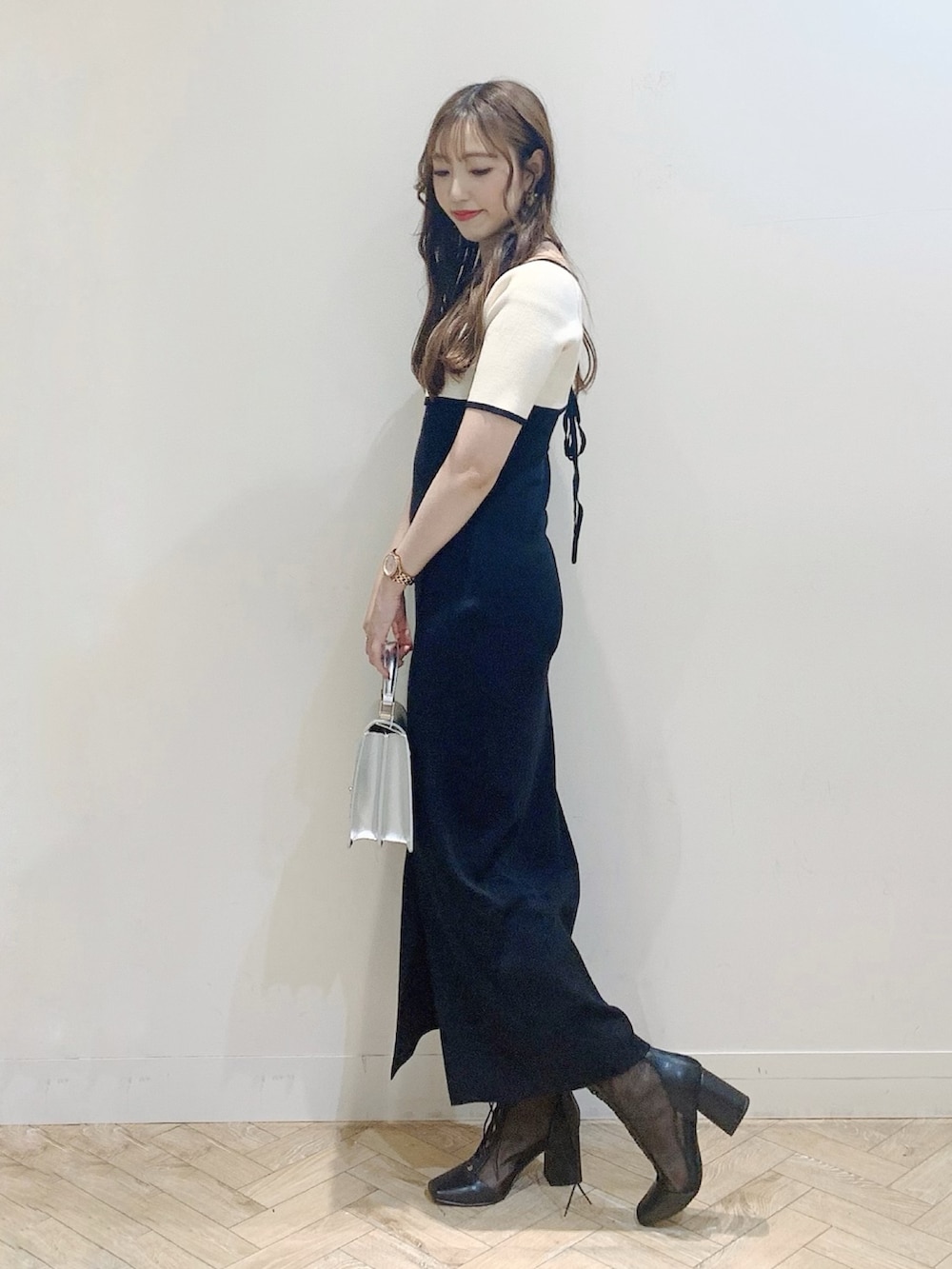 ブラック系のワンピース、シルバー系のハンドバッグ、ブラック系のブーツを着用したレディースの夏コーディネートの4枚目の写真