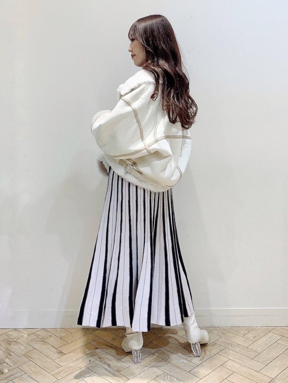 ブラック系のワンピース、ホワイト系のムートンコート、ホワイト系のブーツを着用したレディースの冬コーディネートの7枚目の写真