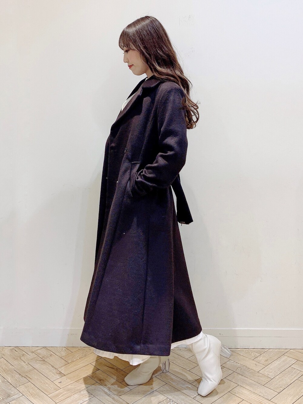 ホワイト系のワンピース、ブラウン系のチェスターコート、ホワイト系のブーツを着用したレディースの冬コーディネートの8枚目の写真