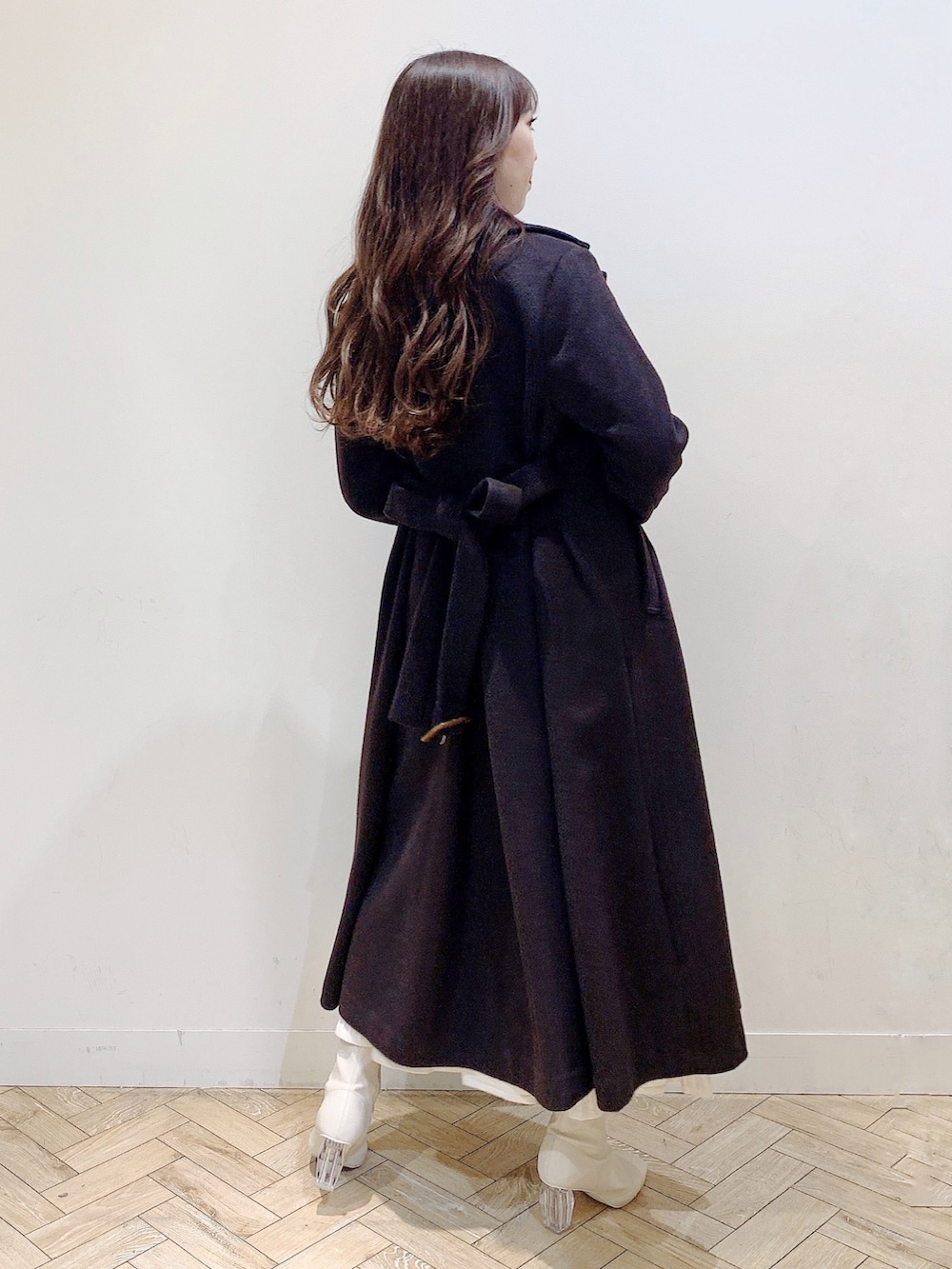 ホワイト系のワンピース、ブラウン系のチェスターコート、ホワイト系のブーツを着用したレディースの冬コーディネートの9枚目の写真