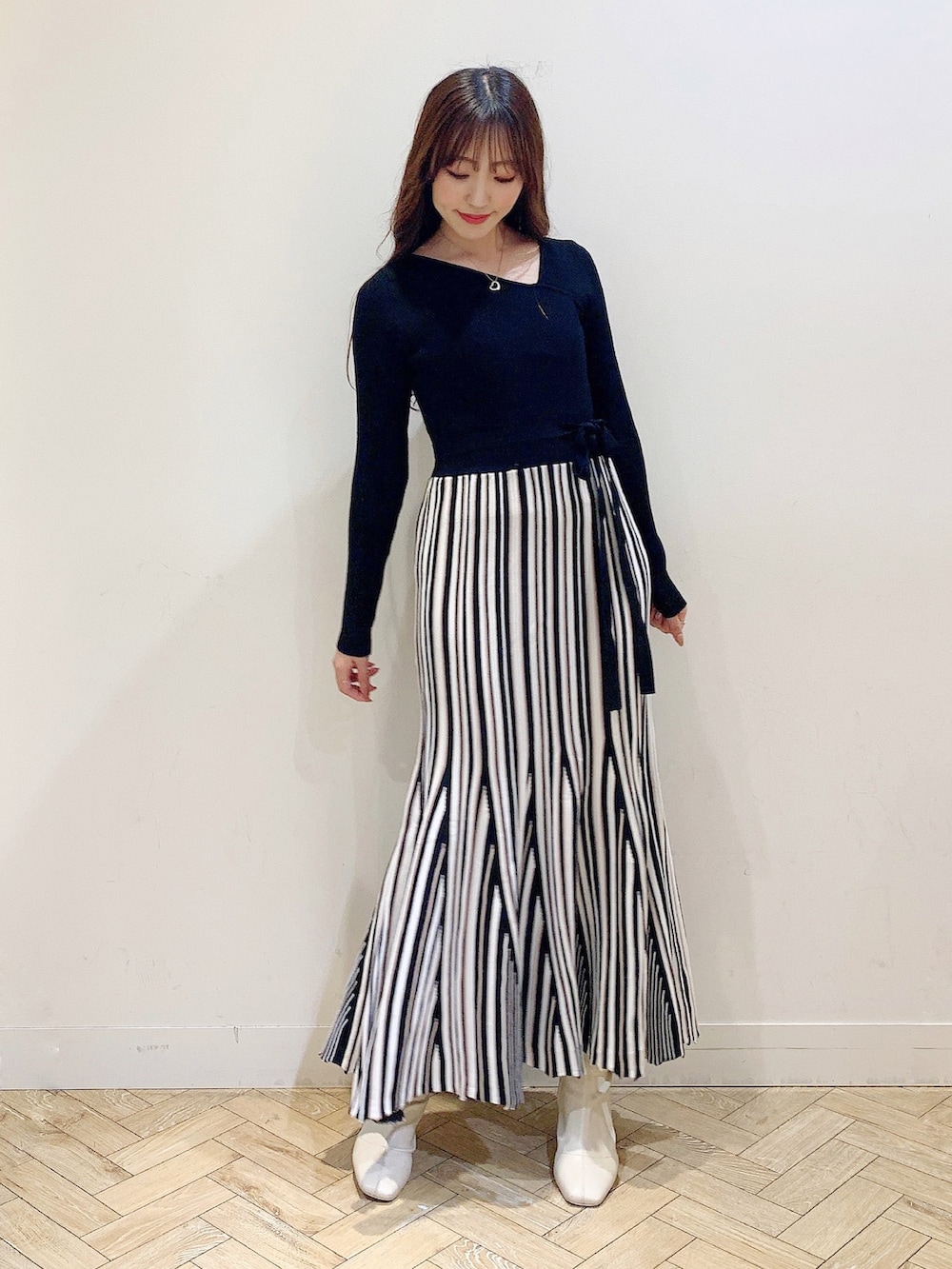 ブラック系のワンピース、ブラック系のダウンジャケット/コート、ホワイト系のブーツを着用したレディースの冬コーディネートの2枚目の写真