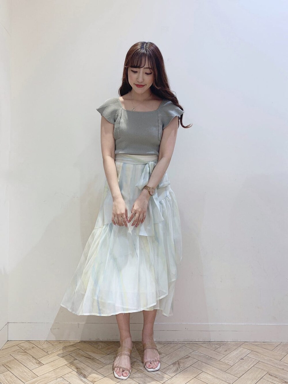 グリーン系のスカート、ベージュ系のサンダル、グリーン系のニット/セーターを着用したレディースの春コーディネートの3枚目の写真