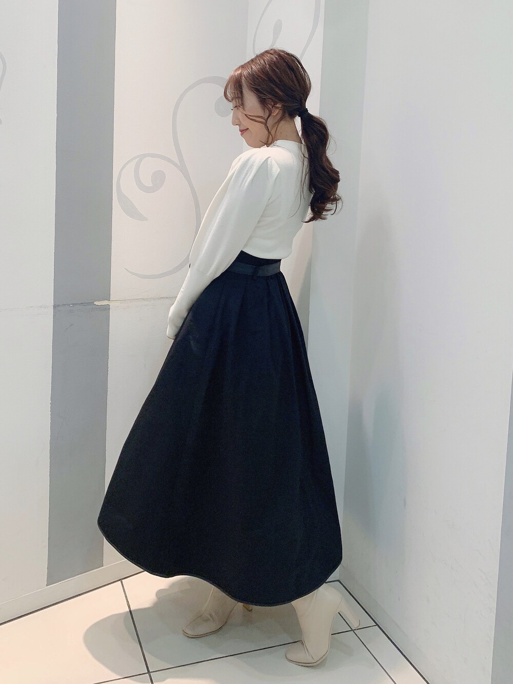 ホワイト系のブーツ、ブラック系のスカート、ホワイト系のニット/セーターを着用したレディースの秋コーディネートの4枚目の写真