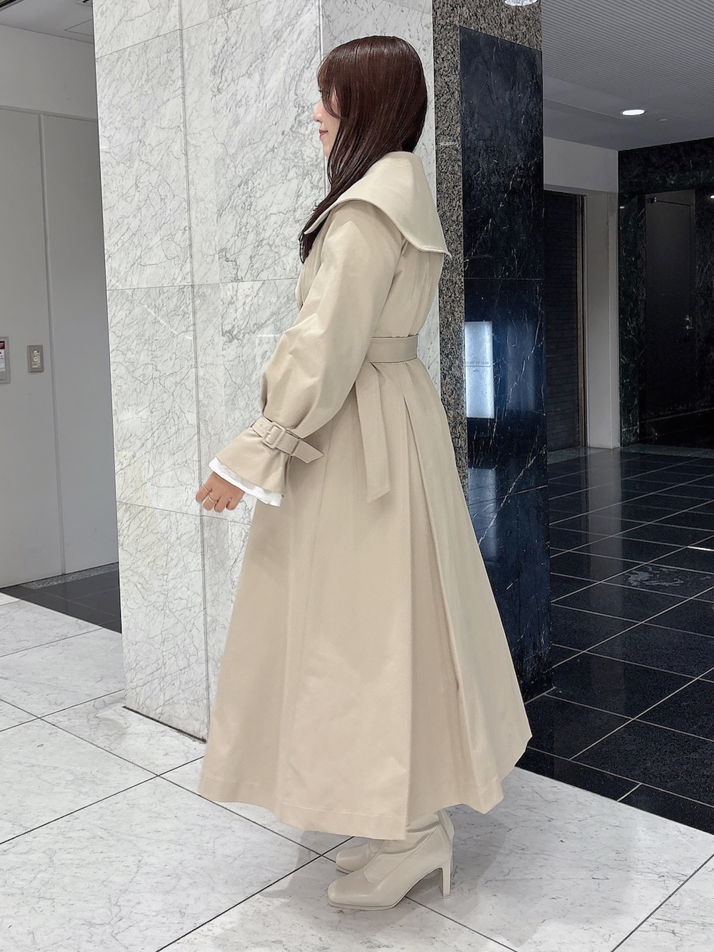ホワイト系のブーツ、ベージュ系のトレンチコート、ホワイト系のワンピースを着用したレディースの冬コーディネートの4枚目の写真