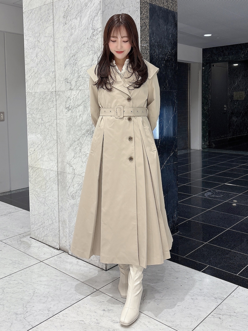 ホワイト系のブーツ、ベージュ系のトレンチコート、ホワイト系のワンピースを着用したレディースの冬コーディネートの3枚目の写真