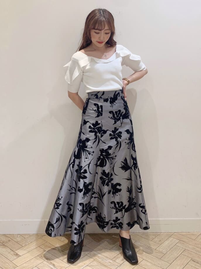 グレー系のスカート、ブラック系のサンダル、ホワイト系のニット/セーターを着用したレディースの夏コーディネートの4枚目の写真