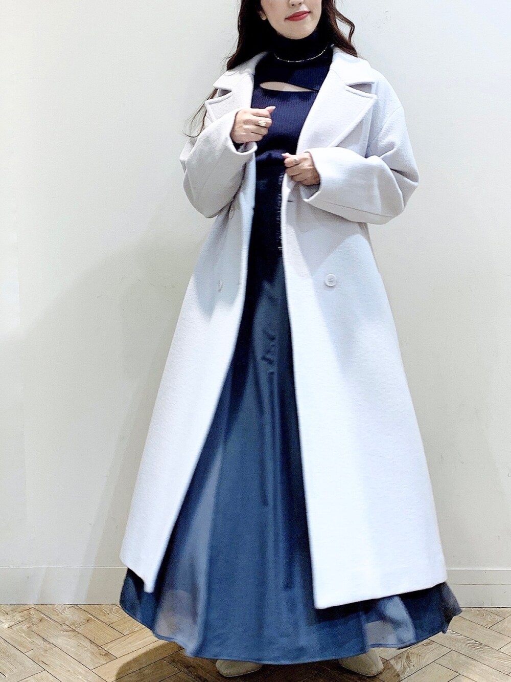 グレー系のニット/セーター、グレー系のスカート、ホワイト系のブーツを着用したレディースの冬コーディネートの8枚目の写真