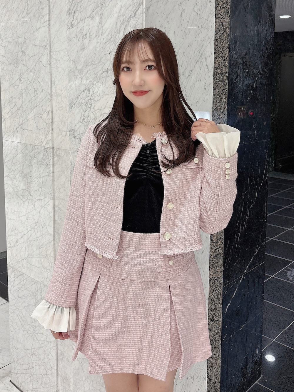 ピンク系のノーカラージャケット、ピンク系のスカート、ホワイト系のブーツを着用したレディースの冬コーディネートの5枚目の写真