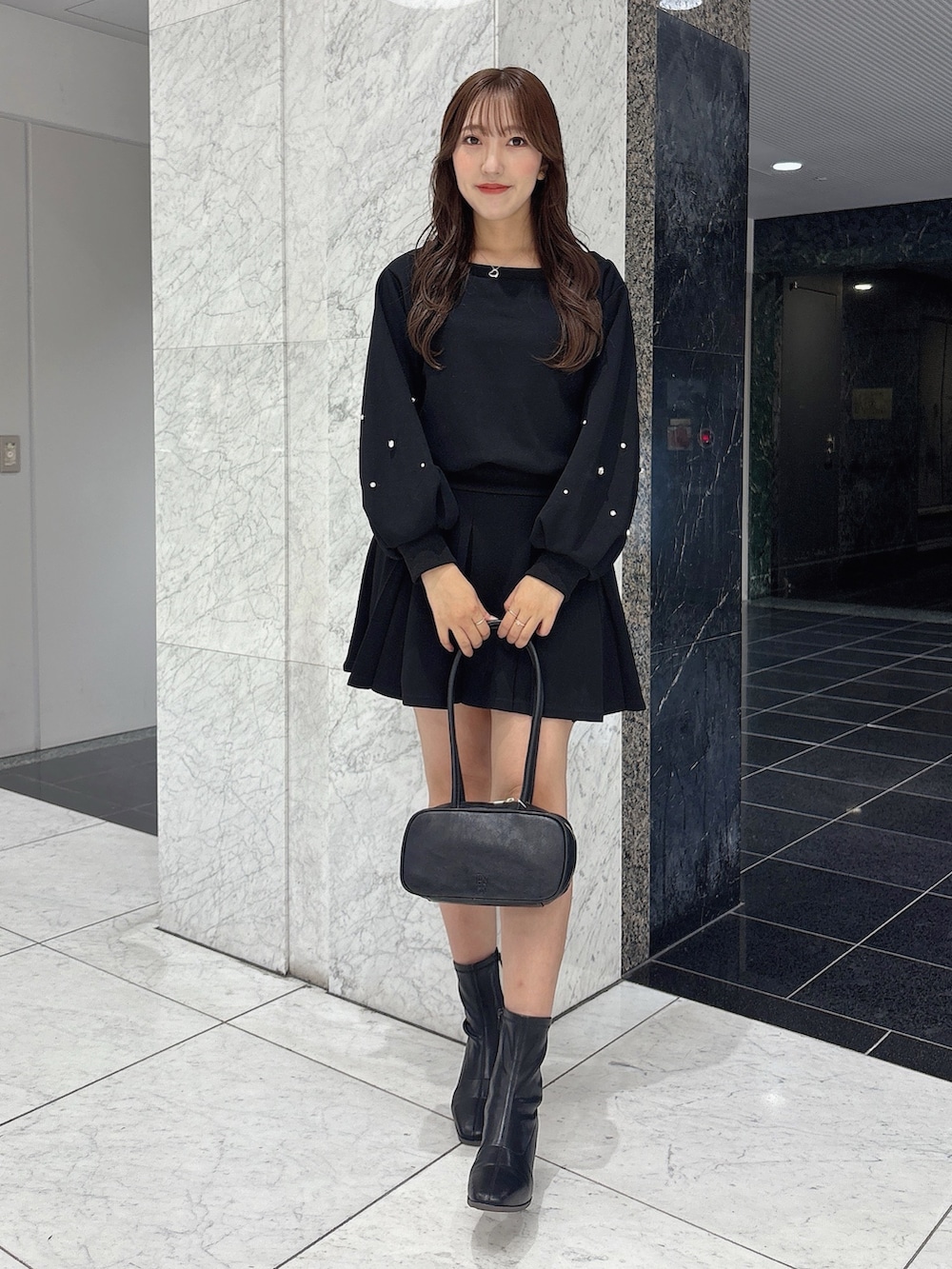 ブラック系のスカート、ブラック系のスウェット、ブラック系のブーツを着用したレディースの秋コーディネートの2枚目の写真