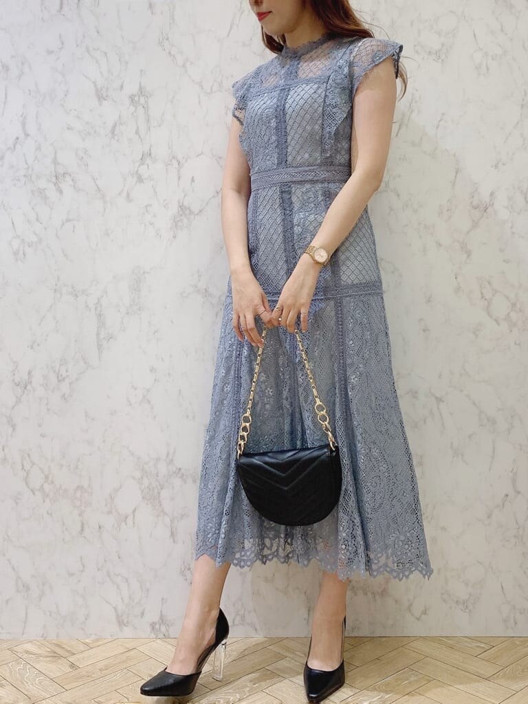 ブルー系のドレス、ブラック系のパンプス、ブラック系のハンドバッグを着用したレディースの夏コーディネートの2枚目の写真
