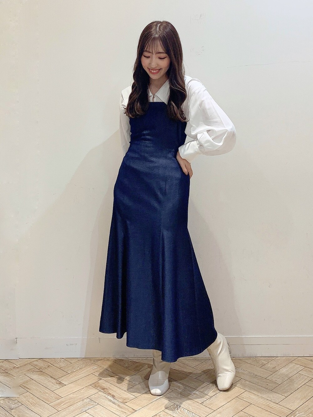 ブルー系のワンピース、ホワイト系のブーツ、ベージュ系のステンカラーコートを着用したレディースの冬コーディネートの2枚目の写真