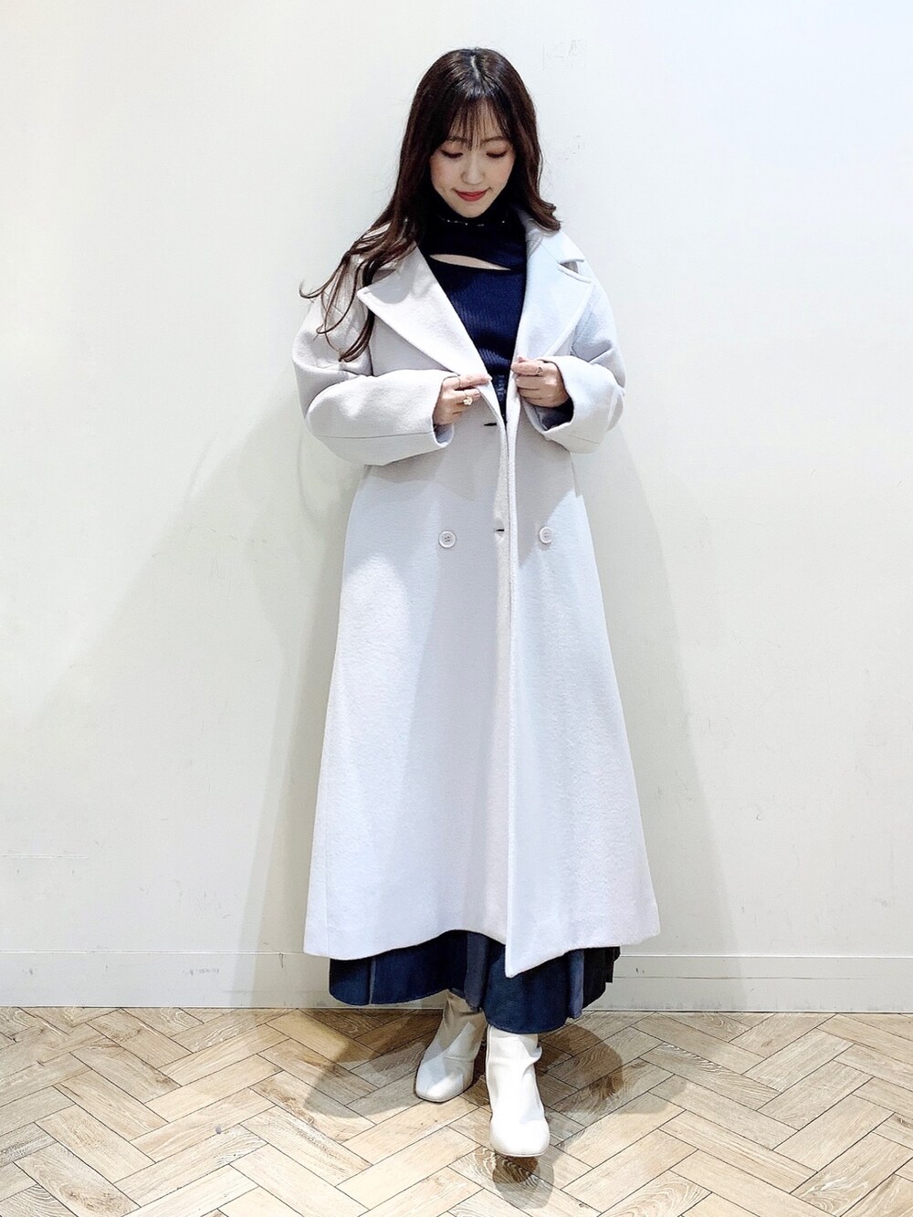 グレー系のニット/セーター、グレー系のスカート、ホワイト系のブーツを着用したレディースの冬コーディネートの7枚目の写真