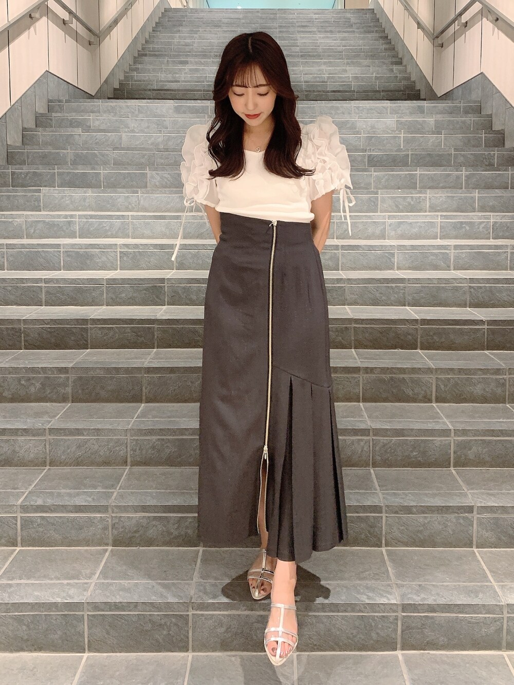 ブラウン系のスカート、シルバー系のパンプス、ホワイト系のTシャツ/カットソーを着用したレディースの夏コーディネートの3枚目の写真