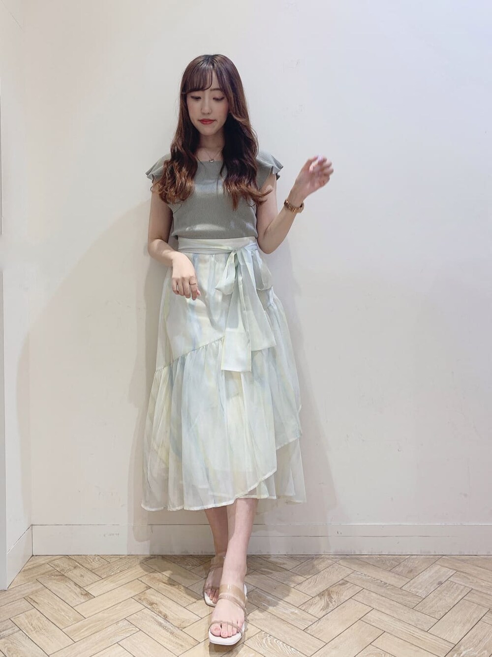 グリーン系のスカート、ベージュ系のサンダル、グリーン系のニット/セーターを着用したレディースの春コーディネートの2枚目の写真