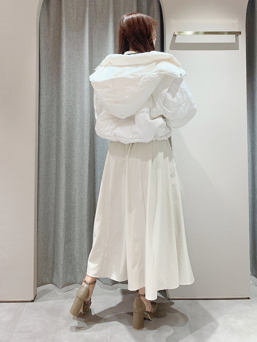 ベージュ系のパンプス、ホワイト系のワンピース、ホワイト系のダウンジャケット/コートを着用したレディースの秋コーディネートの3枚目の写真