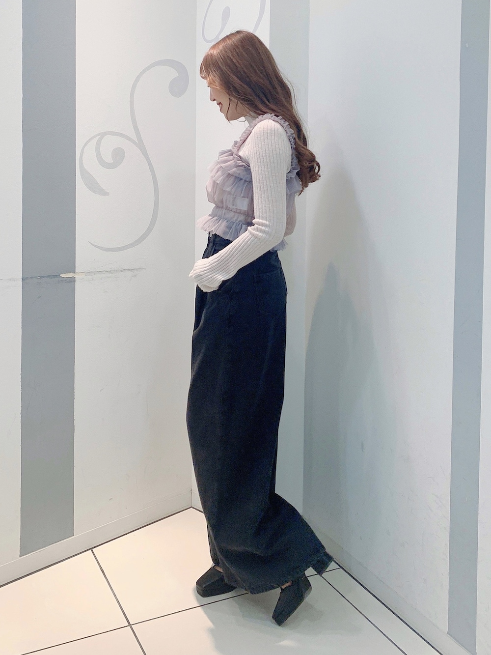 ブラック系のデニムパンツ、ブラック系のパンプス、グレー系のニット/セーターを着用したレディースの秋コーディネートの3枚目の写真