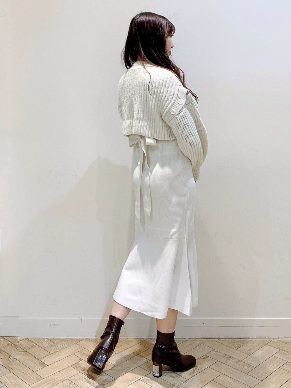 ホワイト系のワンピース、ベージュ系のステンカラーコート、ブラウン系のブーツを着用したレディースの冬コーディネートの4枚目の写真