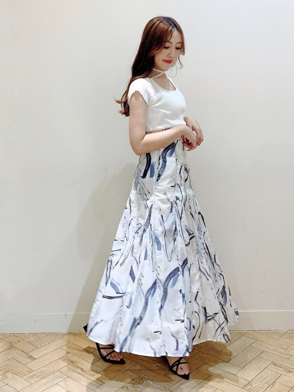 ホワイト系のニット/セーター、グレー系のスカート、ブラック系のサンダルを着用したレディースの夏コーディネートの4枚目の写真