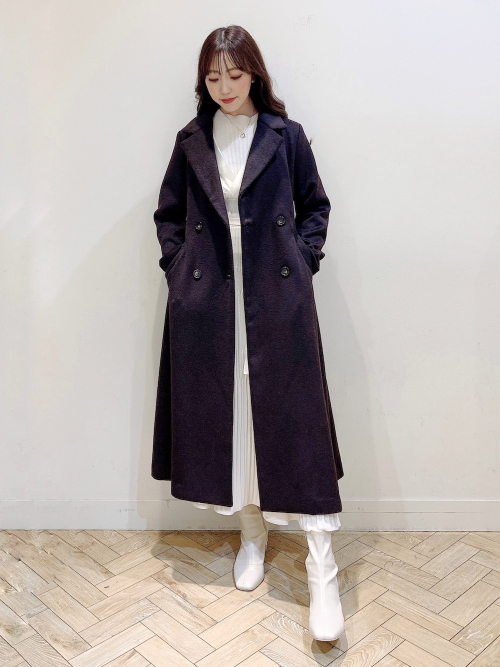 ホワイト系のワンピース、ブラウン系のチェスターコート、ホワイト系のブーツを着用したレディースの冬コーディネートの7枚目の写真