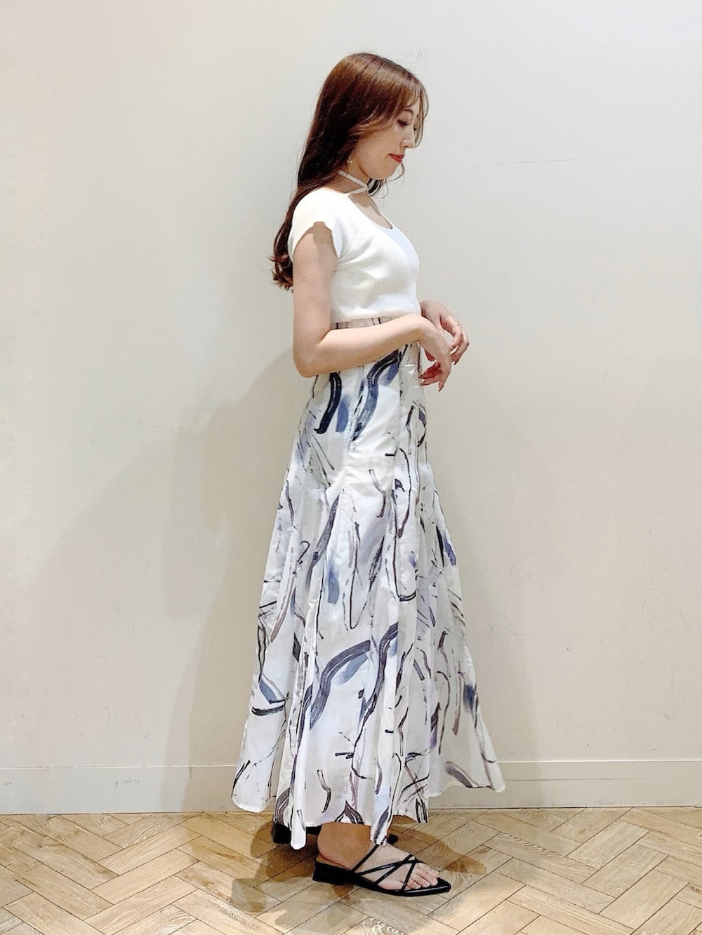 ホワイト系のニット/セーター、グレー系のスカート、ブラック系のサンダルを着用したレディースの夏コーディネートの5枚目の写真